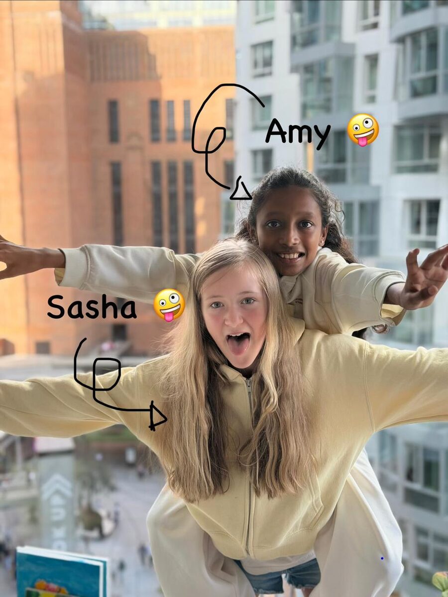 Squish founders Amaaya (Amy) and Sasha pulling silly faces, arms stretched out wide.